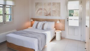 Un dormitorio con cama, mesitas de noche, una puerta y una ventana.
