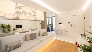 Una sala de estar moderna con pared de mármol, un sofá, una mesa de centro y un comedor.