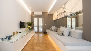 Un interior moderno con una mesa de centro de vidrio, un sofá con cojines y un espejo grande.