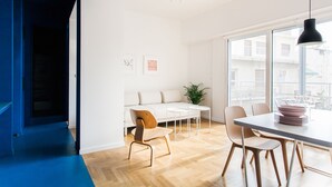 A modern dining area with a wooden table, white chairs, and a black pendant light. - Modern 2 bed/2 bath Acropolis view flat (Αθήνα)