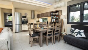 A modern kitchen with a dining area, a sofa, and a window with a view. - A Family Friendly Sea View Villa. Cycling Walking Fishing Birdwatcing Swimming (Πηγαδάκια)