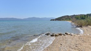 A beach with clear water, pebbles, and a distant mountain range. - A Family Friendly Sea View Villa. Cycling Walking Fishing Birdwatcing Swimming (Πηγαδάκια)
