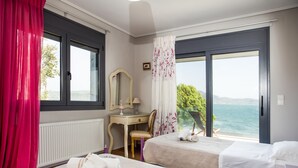 A hotel room with two beds, a desk, a chair, a mirror, and a view of the sea. - A Family Friendly Sea View Villa. Cycling Walking Fishing Birdwatcing Swimming (Πηγαδάκια)