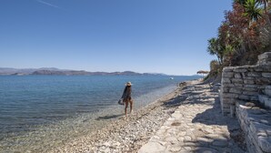 A stone pathway leading to a body of water, with a person walking along it.