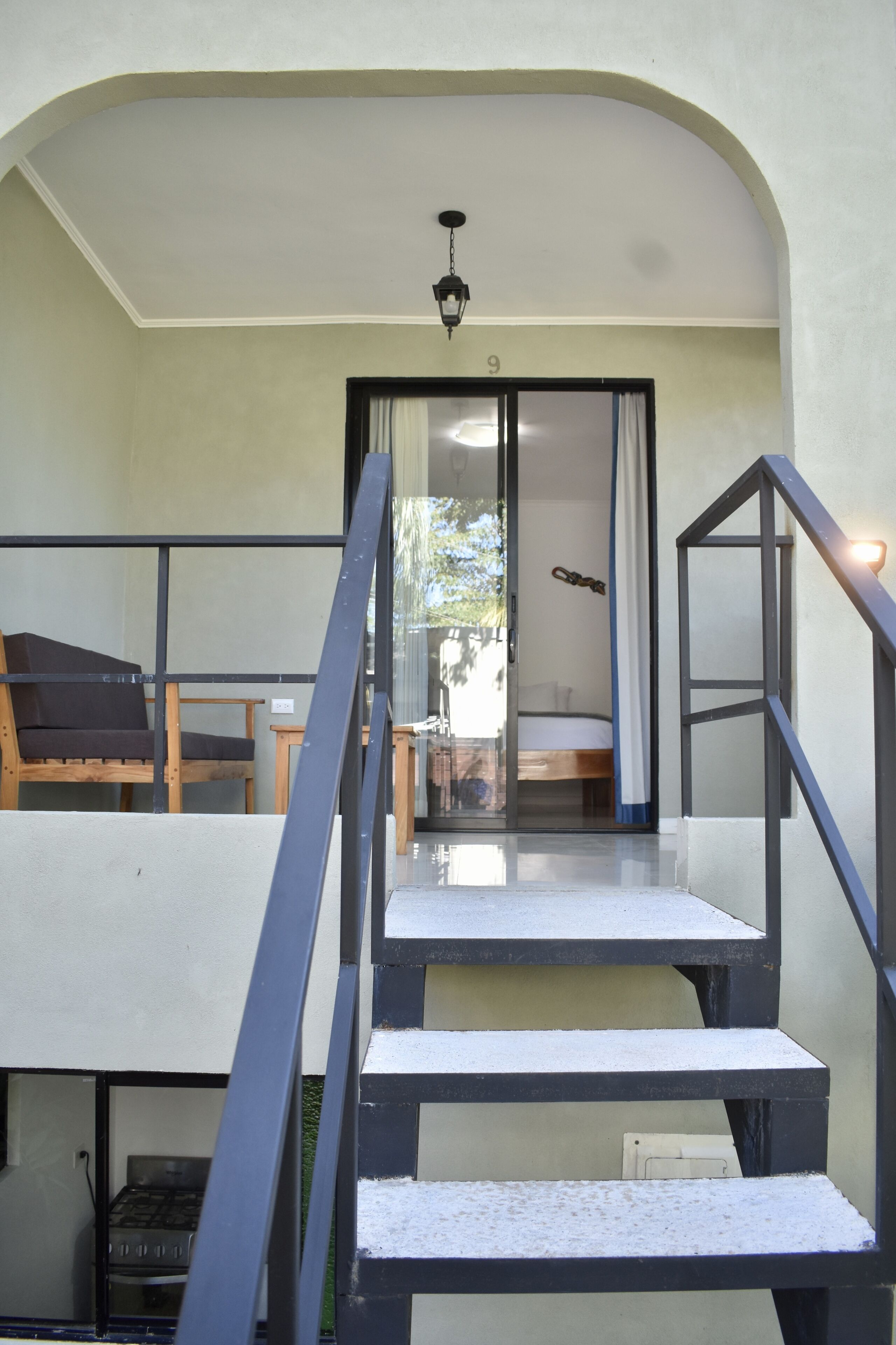 A staircase leading to a bedroom with a bed, a window with curtains, and a view of the outdoors.