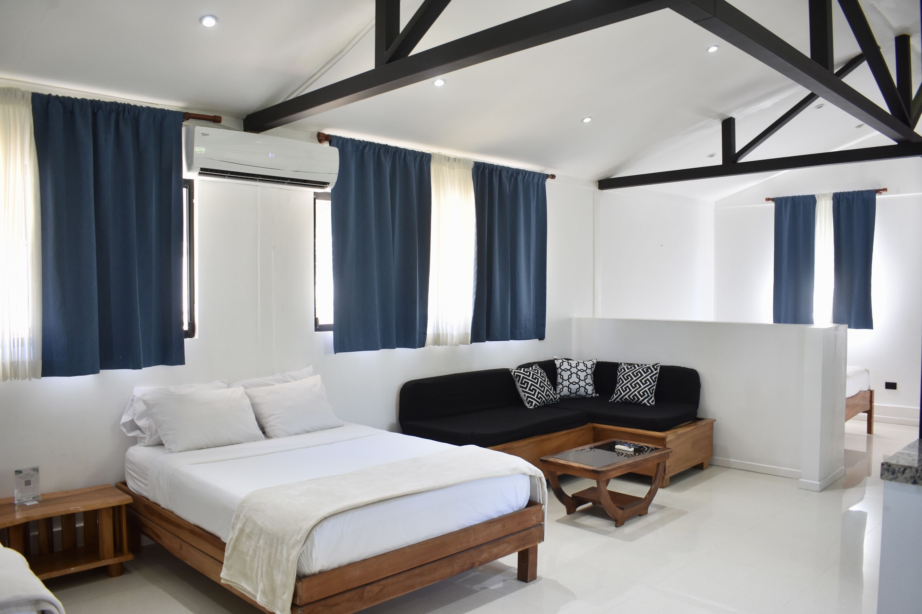 A modern bedroom with a wooden bed, a black sofa, and a wooden coffee table.