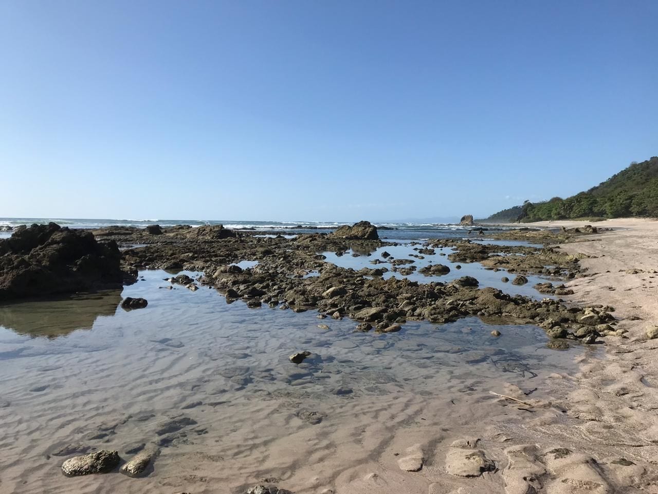 Une plage avec une eau claire, des rochers et un rivage sablonneux.