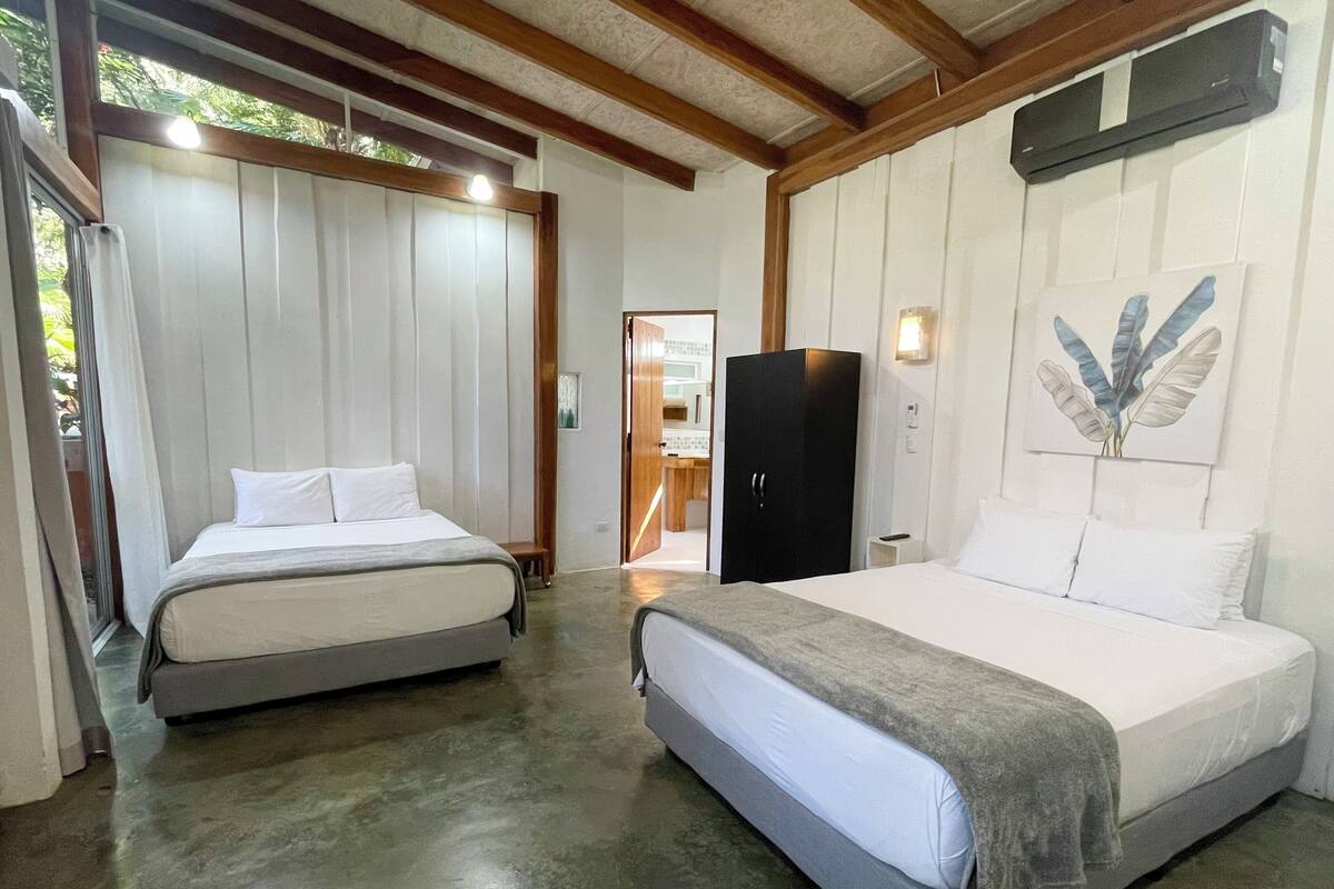 Habitación de hotel con dos camas, un armario, un cuadro y un ventilador de techo.