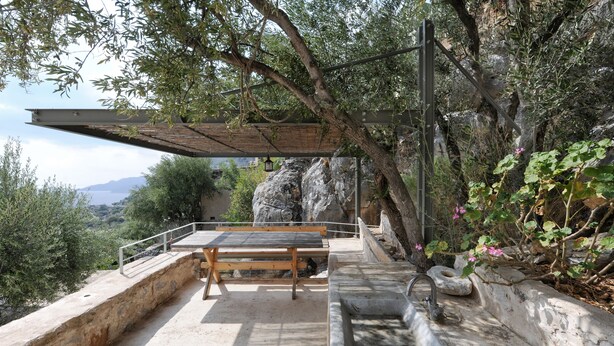 Un banc et un espace lavabo en pierre, offrant une vue sur un paysage rocheux et des arbres.