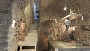 Une cuisine rustique avec des murs en pierre, un escalier en bois et un îlot central en bois doté d’un évier.