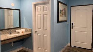 A bathroom with a granite countertop sink, a white door, and a framed picture on the wall. - Redondo Beach Motel (Gardena)