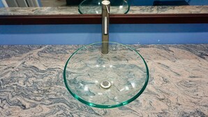 A marble countertop with a glass bowl sink and a faucet. - Redondo Beach Motel (Gardena)