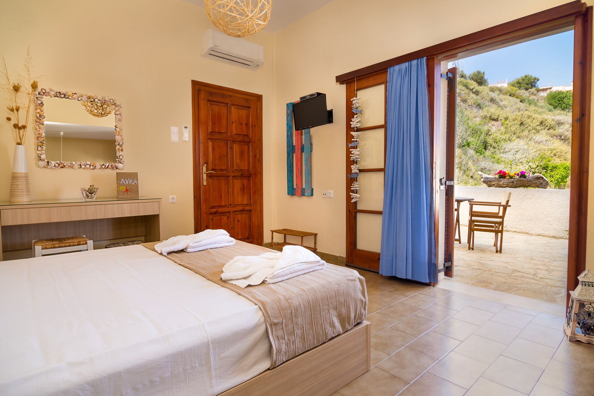 A bedroom with a bed, a wooden door, a TV, and a view of the outside.