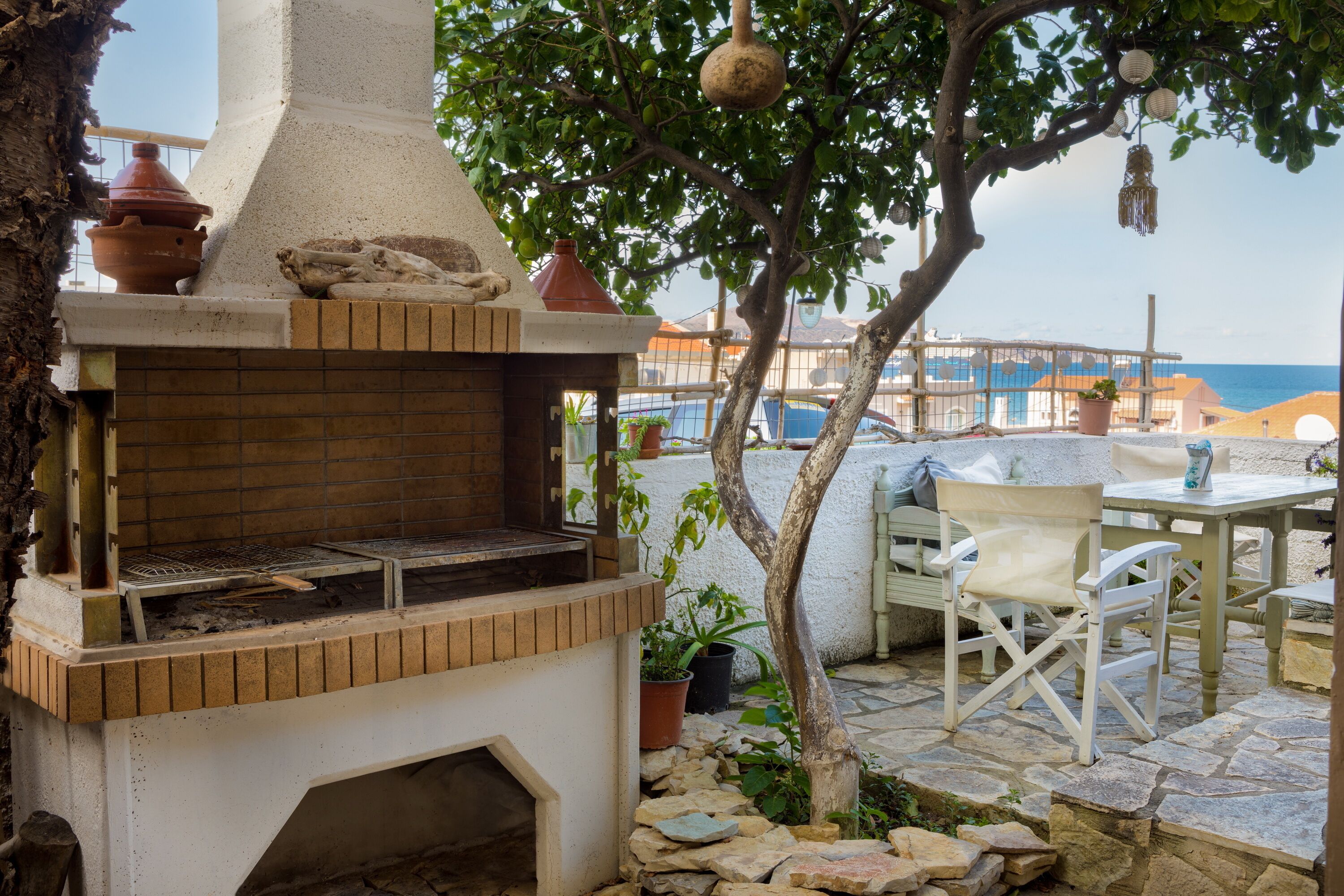 An outdoor kitchen area with a brick oven, potted plants, and outdoor seating.