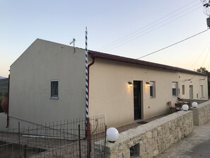A two-story building with a beige exterior, a red roof, and a small porch area with a stone wall. - Maria's Sweet Home. Traditional Renovated house (Καρθιανά)