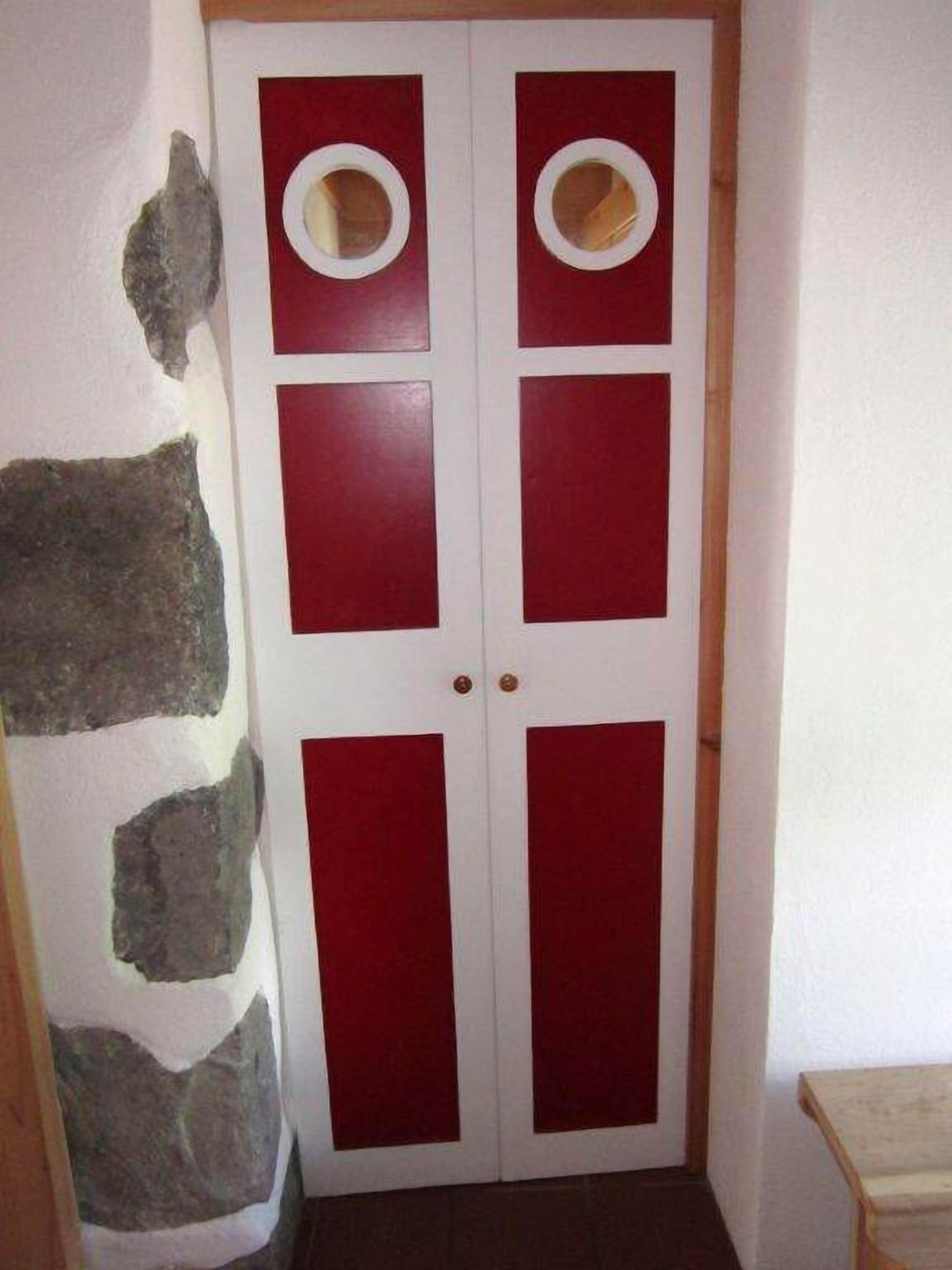 Une porte aux couleurs rouge et blanche, ornée de panneaux circulaires et rectangulaires.