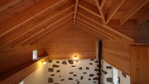 A wooden interior with a sloped ceiling and stone wall. - A small cottage in the center of Horta, Faial Island, Azores (Horta)