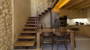 A modern kitchen with a wooden staircase, a dining table with chairs, and a refrigerator. - Seaside 2 floor Maisonette with Jacuzzi (Χανιά)