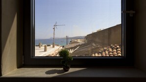 A window with a view of a coastal area, including a beach, construction materials, and a clear sky. - Seaside 2 floor Maisonette with Jacuzzi (Χανιά)