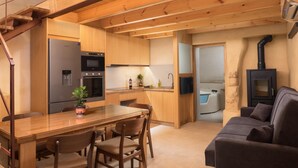 A modern kitchen with wooden cabinets, a built-in oven, and a dining area with a table and chairs. - Seaside 2 floor Maisonette with Jacuzzi (Χανιά)