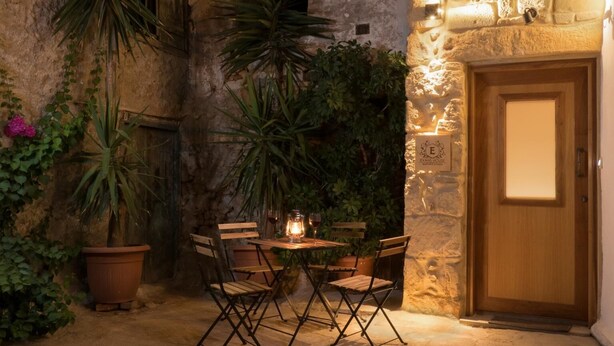 An outdoor patio with a table and chairs, surrounded by potted plants and a stone wall. - Seaside 2 floor Maisonette with Jacuzzi (Χανιά)