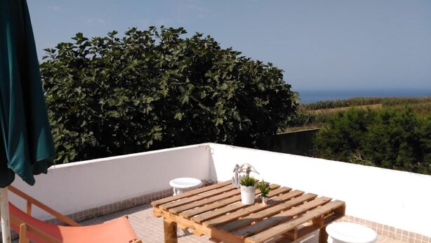 A terrace with a wooden table, two white stools, and a folding chair. - Tia Rosário Casita in Lourinhã (Lourinhã)