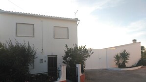 A two-story building with a white facade, a black gate, and a gravel driveway. - Tia Rosário Casita in Lourinhã (Lourinhã)