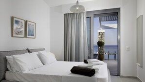 Habitación de hotel moderna con una cama grande, un balcón con vista al mar y dos cuadros enmarcados en la pared.