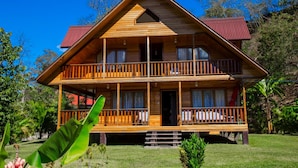 A two-story wooden cabin with a balcony on the upper floor, surrounded by greenery. - Ecolodge Don Felix (Santa Ana)