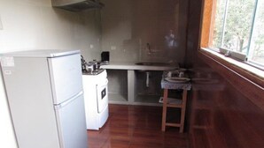 A compact kitchen with a refrigerator, stove, and sink. - Ecolodge Don Felix (Santa Ana)