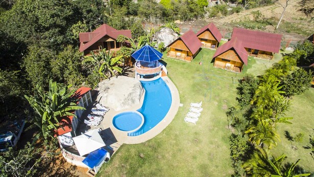 A resort with multiple wooden cabins, a central pool with a slide, and surrounding lush greenery. - Ecolodge Don Felix (Santa Ana)