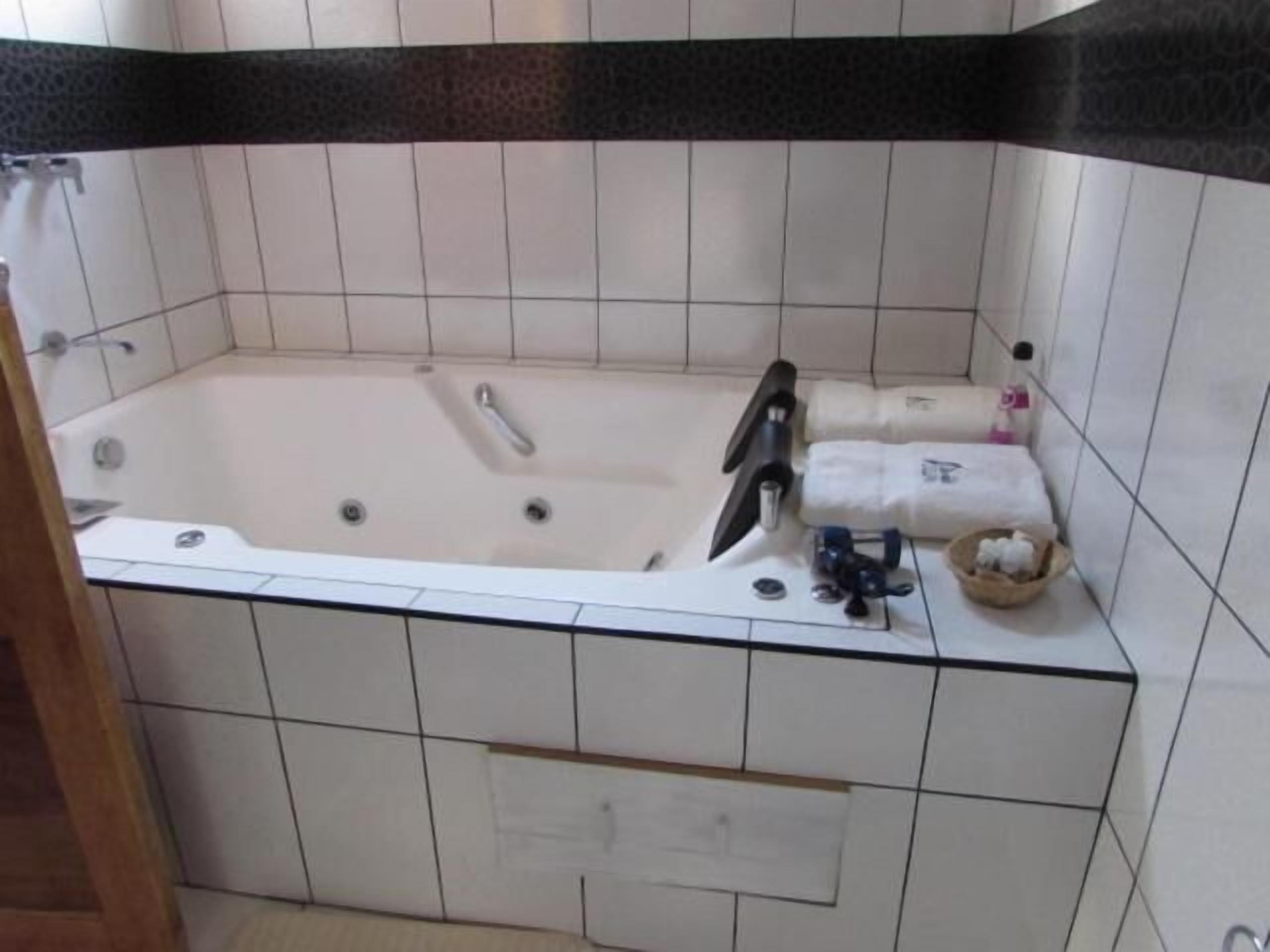 Un bagno con vasca, toilette e lavandino. Asciugamani e articoli da toilette sul bordo della vasca.