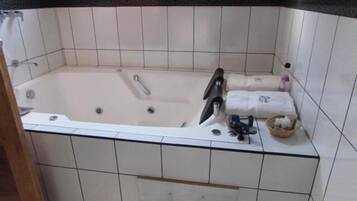 Un bagno con vasca, toilette e lavandino. Asciugamani e articoli da toilette sul bordo della vasca.