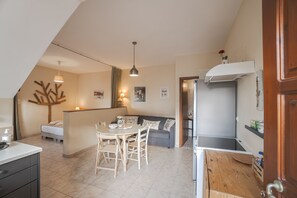 A cozy, well-lit kitchen with a dining area, a gray sofa, and a wooden ceiling. - Avra Apartments, Maistros (Καλύβες)