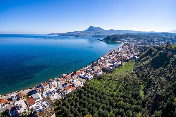 Une ville côtière dotée d’une longue plage, d’un quartier résidentiel dense et d’une colline imposante, avec une montagne en toile de fond.