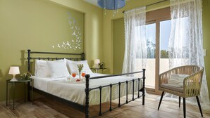 A bedroom with a bed, a chair, a nightstand, a lamp, and a window with curtains.