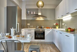 Een moderne keuken met witte kastjes, een ingebouwde oven en een roestvrijstalen afzuigkap.
