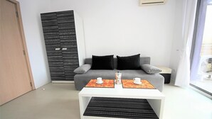 A modern living room with a grey sofa, black and white patterned sideboard, and a white coffee table with two cups and a teapot.