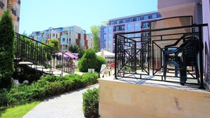 A pathway leading to a building with a metal fence and outdoor seating area.
