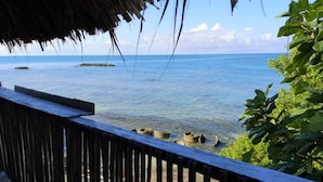 A wooden deck overlooking a clear blue sea with rocky formations. - Dahlandia (Isla Mucura)