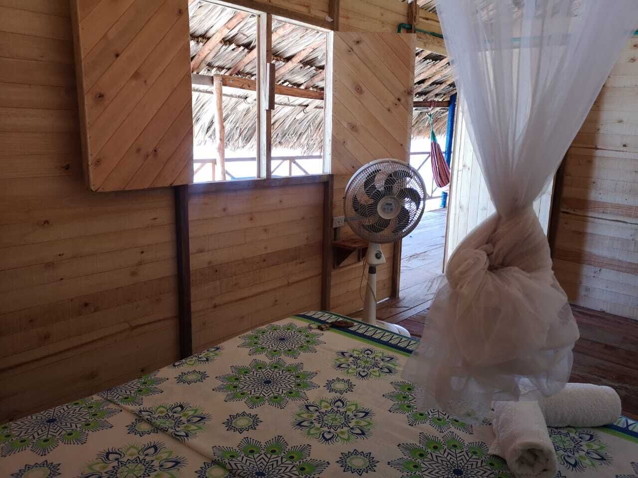 Une chambre avec un lit, un ventilateur et une moustiquaire.