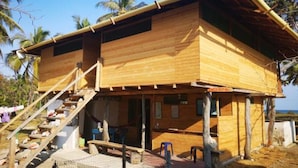 A wooden building with a staircase leading to a covered porch. - Dahlandia (Isla Mucura)