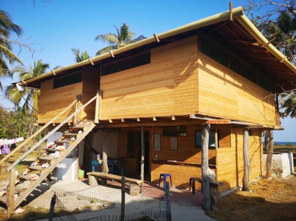 A wooden building with a staircase leading to a covered porch. - Dahlandia (Isla Mucura)