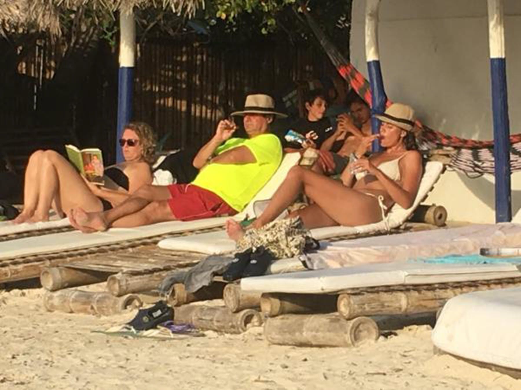 En strandscen med människor som kopplar av på solstolar.