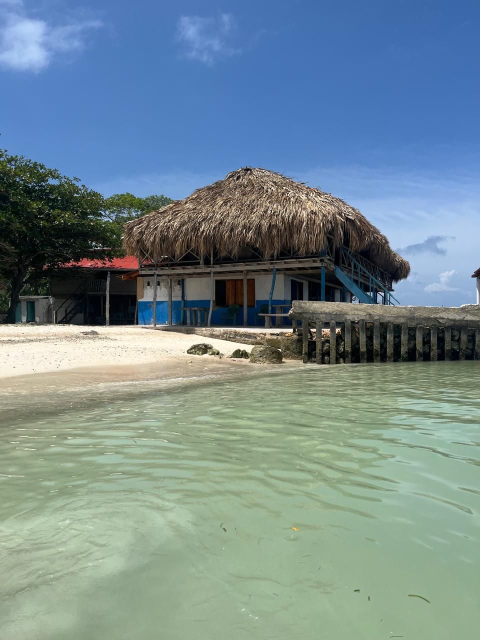 Una propiedad frente a la playa con una estructura de techo de paja, arena y agua cristalina.