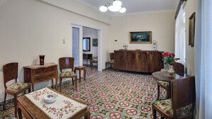 Un saló tradicional amb una catifes amb dibuixos, mobles de fusta, una taula de dinar i un quadre a la paret.