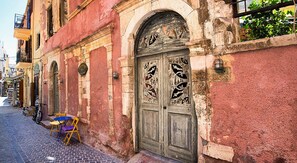 A historic building with a large ornate wooden door, a bicycle parked outside, and a small table with chairs on the sidewalk.
