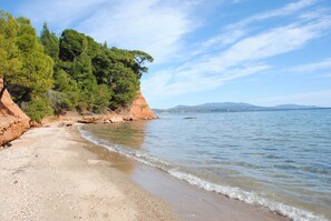 A beach with clear waters, a sandy shore, and a rocky cliff with trees. - Daniil's Seafront Apartment  (Νικήτη)