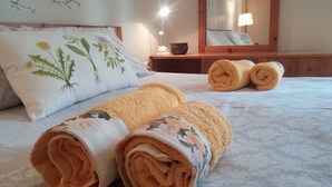 A neatly made bed with rolled towels and a floral pillow. - Daniil's Seafront Apartment  (Νικήτη)