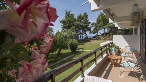 A balcony with a wooden railing, a table, and two chairs. - Daniil's Seafront Apartment  (Νικήτη)